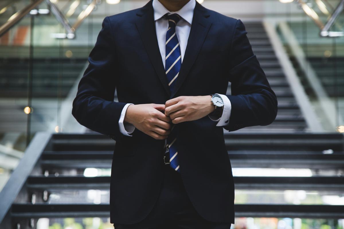 An artificial intelligence generated headshot of a man in a suit and tie with a neutral background